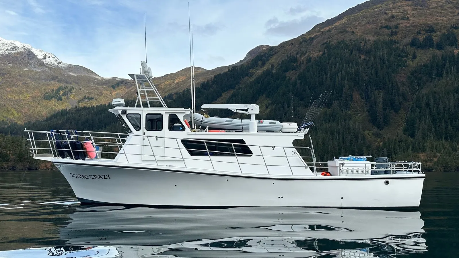 The F/V Sound Crazy on still water below forested mountains